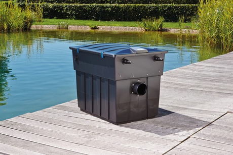 A black gravity filter pictured beside a large pond